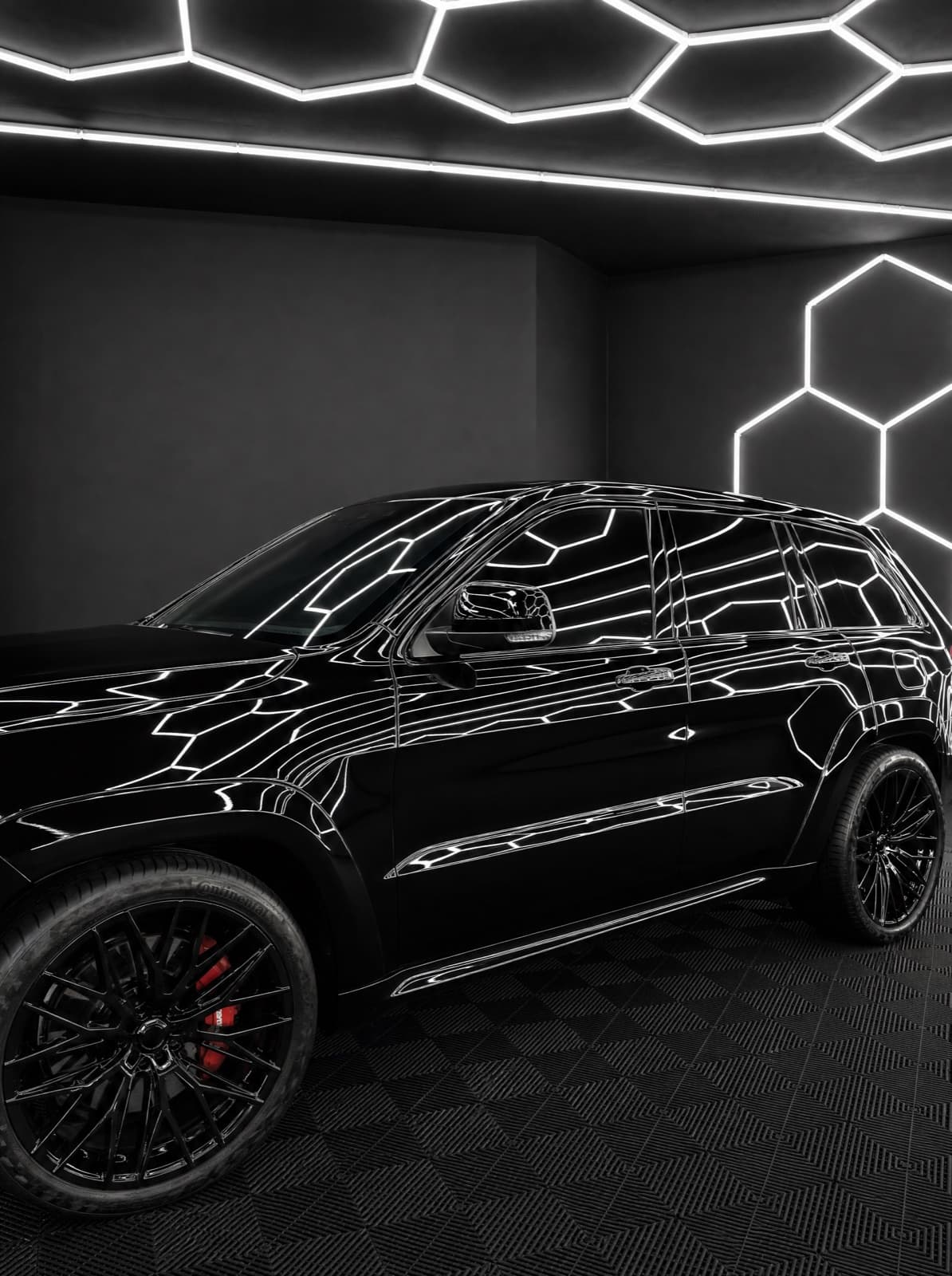 Gloss-black Jeep Grand Cherokee SRT mirroring the studio hexagon lighting