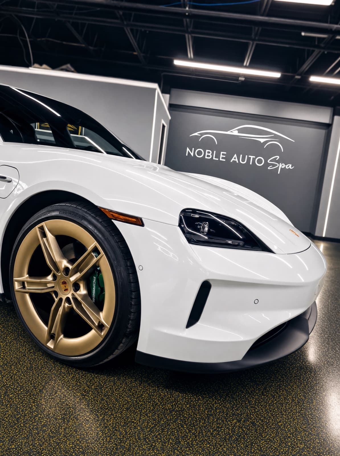 White Porsche Taycan with gold wheels in the Noble Auto studio